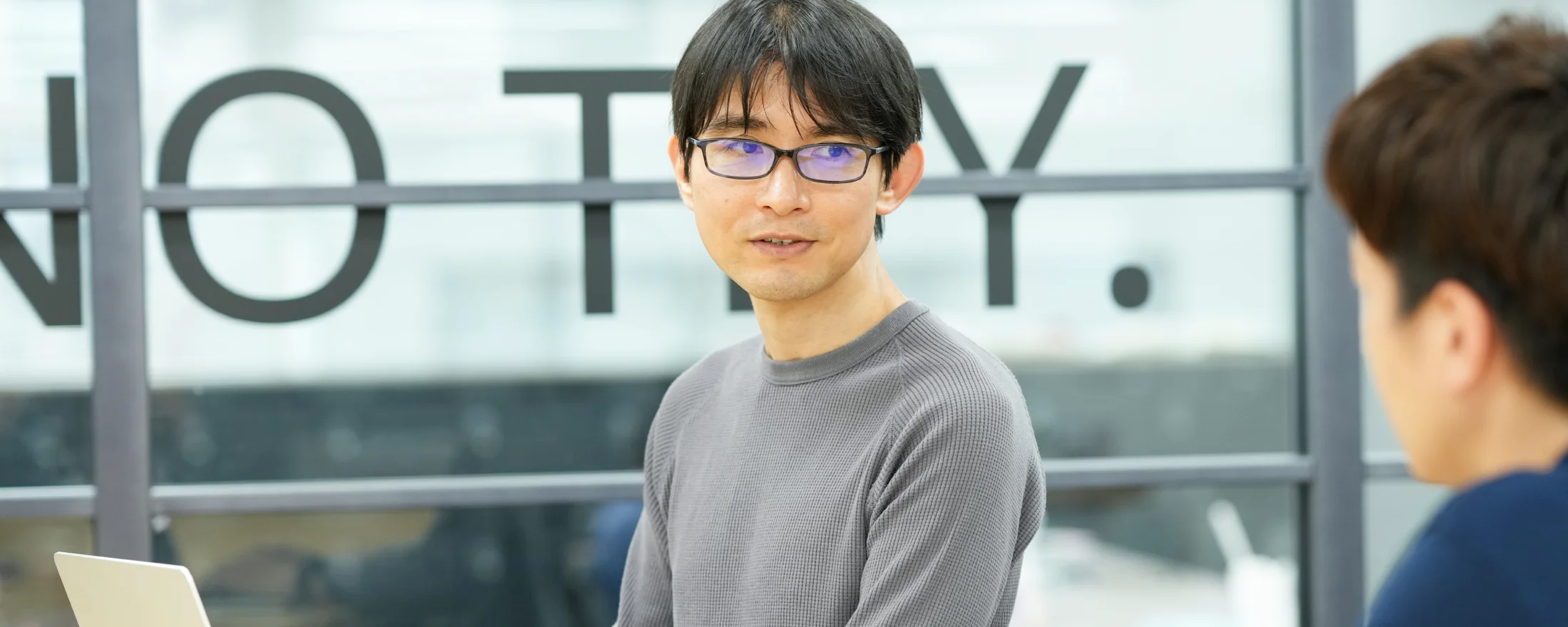 ノートパソコンを囲んで話す社員たち