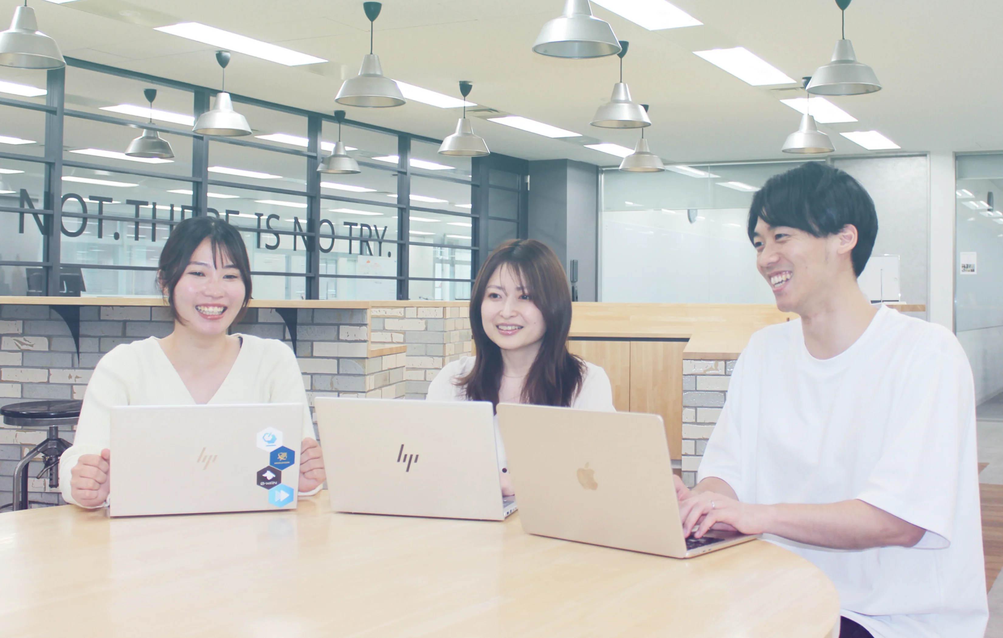 ノートパソコンを囲んで談笑する社員たち
