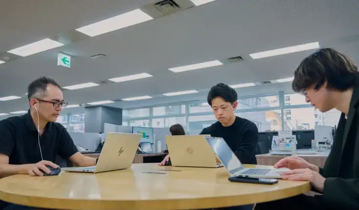 ノートパソコンで作業するエンジニアたち
