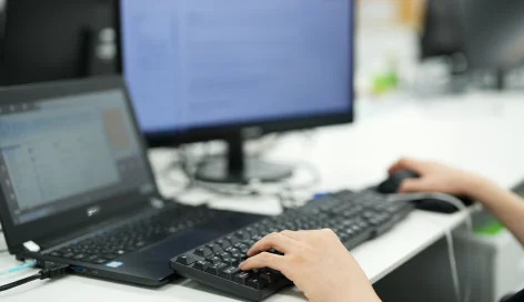 ノートパソコンをタイピングする手元
